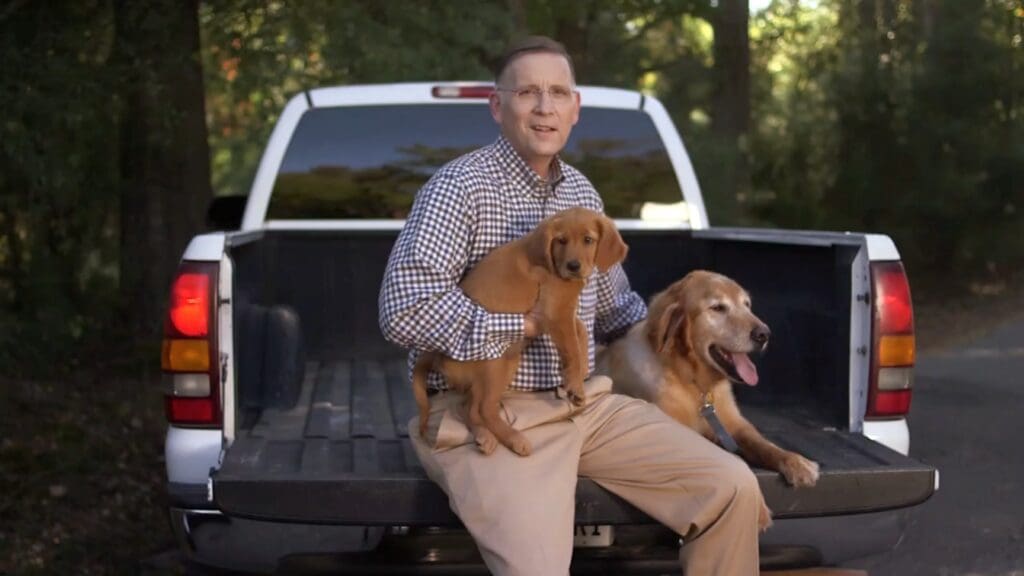 attorney holding a golden retriever puppy in the back of a truck
